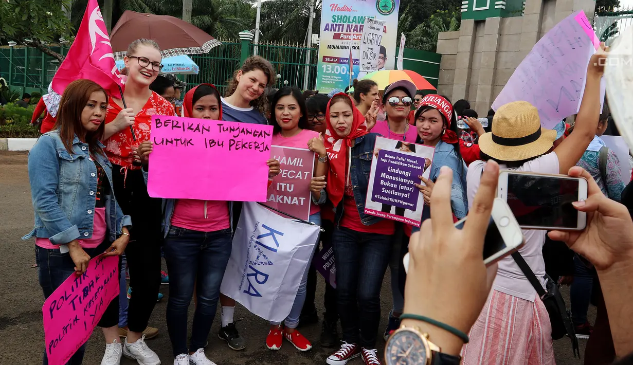 Aktivis Parade Juang Perempuan Indonesia berpose dengan turis asing saat demontrasi di depan Gedung DPR, Jakarta, Kamis (8/3). Kemerdekaan perempuan yang dituntut meliputi di tengah masyarakat maupun dalam pekerjaan. (Liputan6.com/JohanTallo)