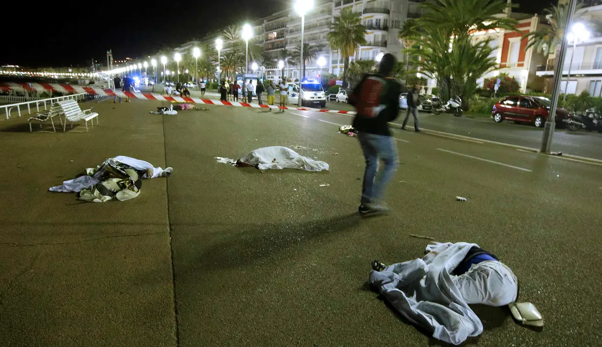 Seorang pria melintas di antara jasad korban serangan teror truk di jalanan kota Nice, Prancis, Kamis (14/7). Setidaknya 60 orang tewas saat sebuah truk menabrak kerumunan ramai yang merayakan libur nasional Bastille Day. (REUTERS/Eric Gaillard)