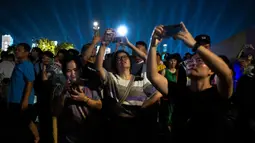 Warga yang antusias menyaksikan pertunjukan cahaya di Hangzhou Olympic Sports Centre Stadium tampak mengabadikan momen indah tersebut dengan ponsel mereka. (Philip FONG/AFP)