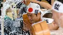 Penganut agama Shinto melakukan mandi air dingin di Kuil Kanda, Tokyo, Jepang (13/1). Upacara ini diawali dengan pemberkatan oleh pendeta. Acara dilanjutkan dengan lari pagi mengelilingi kuil. (AFP Photo/Toshifumi Kitamura)