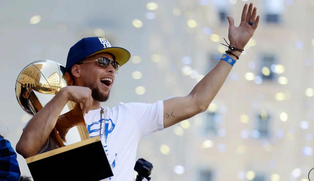 Pemain Guard Golden State Warriors, Stephen Curry memeluk tropi Larry O'Brien saat menggelar parade Warriors 2018 usai menjuarai NBA 2018 di pusat kota Oakland, California, Amerika Serikat, (12/6). (AP Photo/Marcio Jose Sanchez)