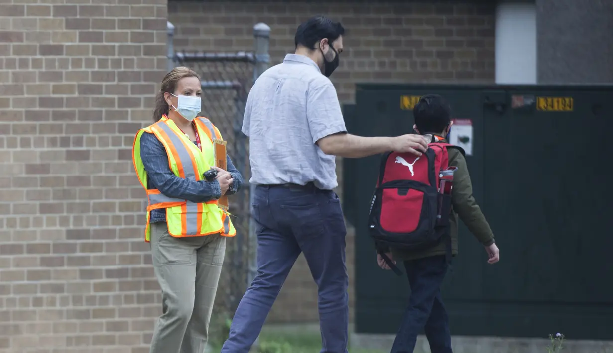 Seorang murid bersama ayahnya tiba di sebuah sekolah di Mississauga, Ontario, Kanada (9/9/2020). Beberapa sekolah di Ontario dibuka kembali pada Rabu (9/9), menawarkan kombinasi kelas tatap muka dan pembelajaran daring (online) bagi para murid. (Xinhua/Zou Zheng)