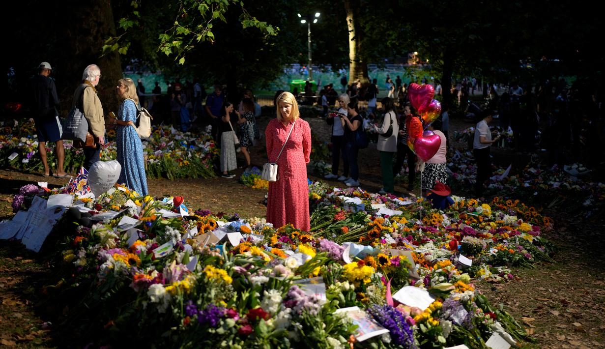 <p>Seorang wanita membaca pesan yang ditempatkan di antara karangan bunga untuk Ratu Elizabeth II di Green Park, dekat Istana Buckingham di London, Senin (12/9/2022). Sebelum menjabat Ratu Inggris, Elizabeth menerima pendidikan di rumah melalui guru pribadinya yang bernama Henry Marten. (AP Photo/Markus Schreiber)</p>