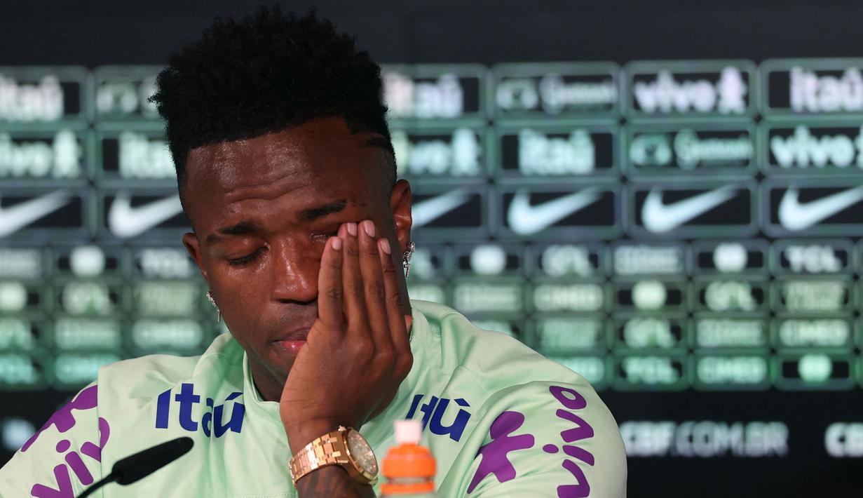 Pemain Brasil, Vinicius Jr menyeka air mata saat konferensi pers menjelang laga persahabatan melawan Spanyol di tempat latihan Ciudad Real Madrid di Valdebebas, pinggiran Madrid, pada 25 Maret 2024. Laga tersebut memiliki slogan "Satu Kulit" untuk membantu memerangi rasisme. (AFP/Pierre-Philippe Marcou)
