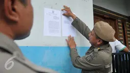 Satpol PP menempelkan surat peringatan kedua (SP2) di salah satu rumah warga di Kalijodo, Jakarta, Kamis (25/2). Dalam SP2 tersebut, warga Kalijodo diberi waktu 3×24 jam untuk mengosongkan/membongkar sendiri bangunan mereka. (Lputan6.com/Gempur M Surya)