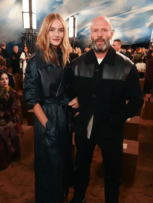Hadir bersama Jason Statham, Rosie Huntington-Whiteley membalut tubuhnya dengan trench coat kulit. [Burberry]