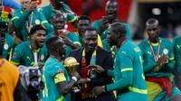 Pelatih kepala Senegal, Pape Thiaw (C), dan tim merayakan kemenangan dengan trofi setelah memenangkan pertandingan final Piala Afrika (CAN) 2025 melawan Maroko di Stadion Pangeran Moulay Abdellah di Rabat, Senin (19-1-2026) dini hari WIB. (Abdel Majid BZIOUAT/AFP)