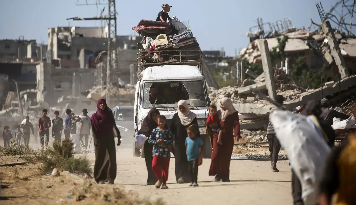 Seorang anak duduk di atas kendaraan yang dipenuhi barang-barang saat pengungsi Palestina kembali ke rumah mereka di kawasan al-Zahra, utara kamp pengungsi Nuseirat di Jalur Gaza tengah, pada Selasa 14 Oktober 2025. (Eyad BABA/AFP)