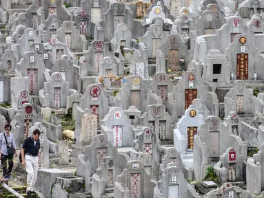 Sepasang warga mengunjungi makam kerabat saat Festival Chung Yeung atau juga dikenal Tomb Sweeping Day di sebuah pemakaman di Hong Kong, 17 Oktober 2018. Festival ini adalah hari untuk menghormati dan mengingat leluhur keluarga. (Anthony WALLACE/AFP).
