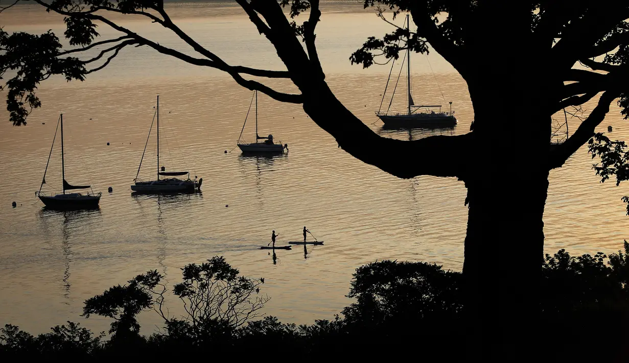 Dua wanita berlatih paddleboarder di perairan tenang Casco Bay, di sebelah Eastern Promenade di Portland, Maine (21/8/2019). Portland memilik jumlah penduduk seramai 67,067 orang pada tahun 2017. (AP Photo/Robert F. Bukaty)