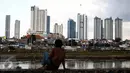 Seorang warga memandangi permukiman kumuh diantara gedung pencakar langit di kawasan Petamburan, Jakarta, Senin (11/7).11 Juli merupakan hari populasi dunia.  (Liputan6.com/Faizal Fanani)