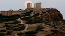 Pengunjung menyaksikan pemandangan bulan purnama hampir penuh yang menampakkan diri di langit Kuil Poseidon kuno di Cape Sounion, sekitar 70 kilometer sebelah tenggara Athena, Yunani (2/8/2020). (Xinhua/Marios Lolos)