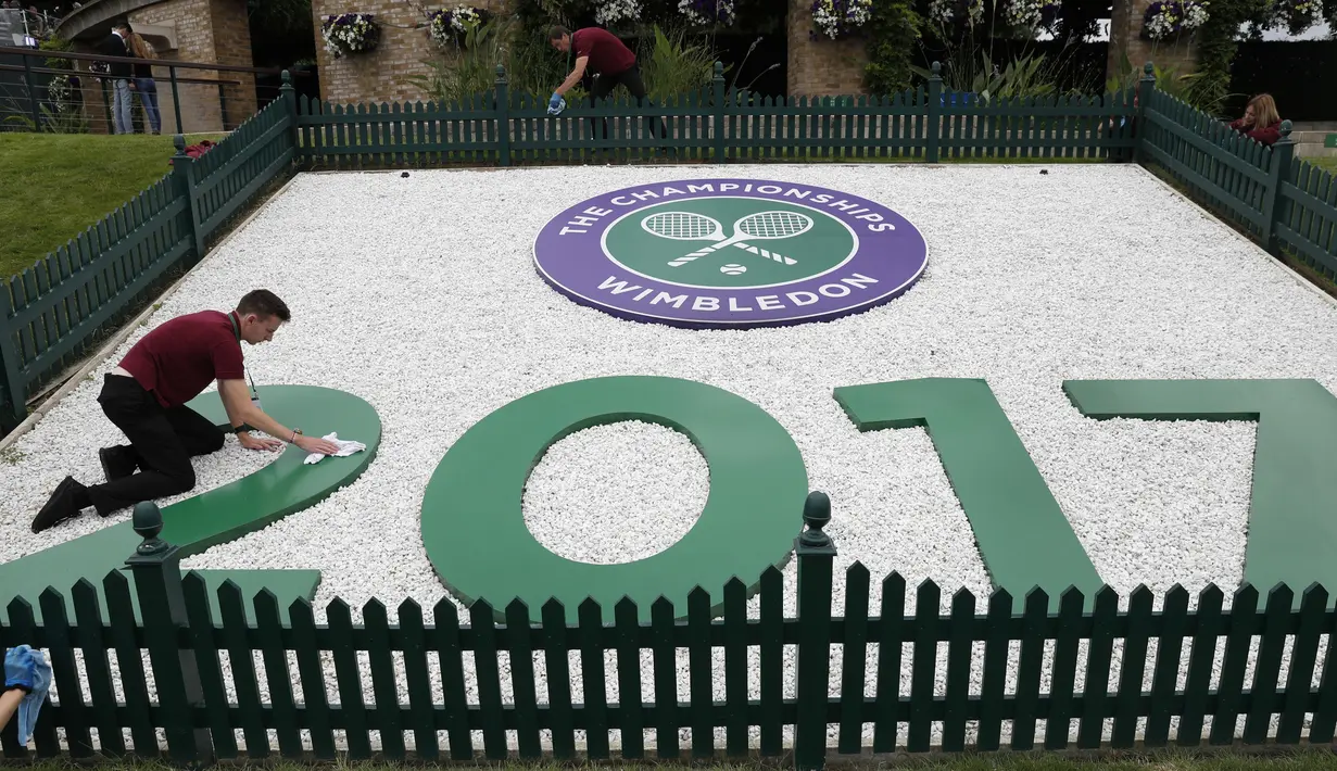 Petugas membersihkan logo Wimbledon 2017 di Wimbledon tennis club, London, (1/7/2017). Turnament Wimbledon 2017 akan berlangsung pada  3-16 Juli 2017. (AFP/Adrian Dennis)