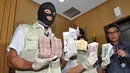 Petugas memperlihatkan barang bukti berupa mata uang dollar AS dan dollar Singapura yang ditemukan dalam operasi tangkap tangan terhadap Gubernur Riau Annas Maamun, Jakarta, (26/9/14). (Liputan6.com/Miftahul Hayat) 