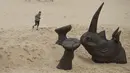 Pengunjung mengambil gambar patung kepala badak raksasa yang dipamerkan di pantai Tamarama di Sydney, Rabu (19/10). Pameran yang bernama ‘Sculpture by the sea’ merupakan pameran patung tahunan diluar ruangan yang terbesar di Australia. (PETER PARKS/AFP)