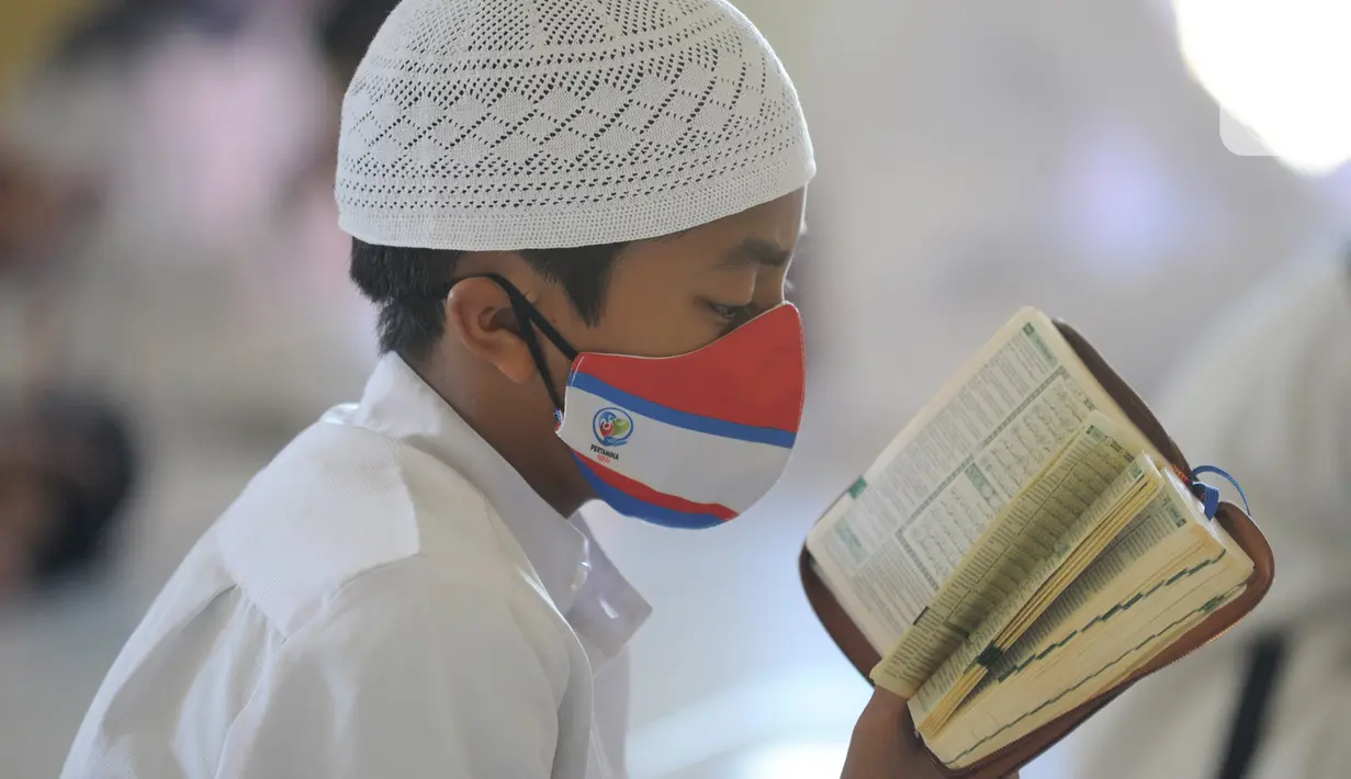 Santri berusia belasan tahun membaca Al quran atau tadarus bersama-sama dengan menerapkan jaga jarak di Masjid Daarul Qu'ran Pesantren Al Kautsar, Cibinong, Bogor, Kamis (7/5/2020). Kegiatan Khatam Al quran tersebut dilakukan rutin di setiap bulan Ramadan. (merdeka.com/Arie Basuki)