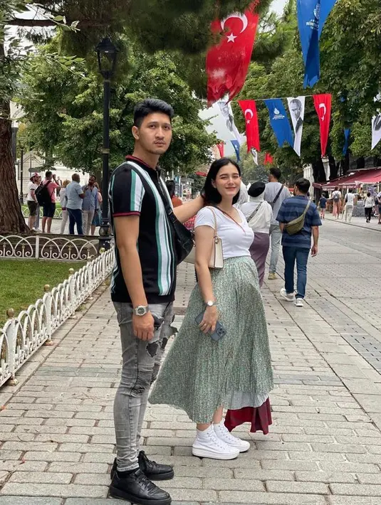 Gayanya itu disempurnakan dengan high sneakers berwarna putih dan shoulder bag warna senada. (Instagram/real_aditya1/yxsmine.ow).