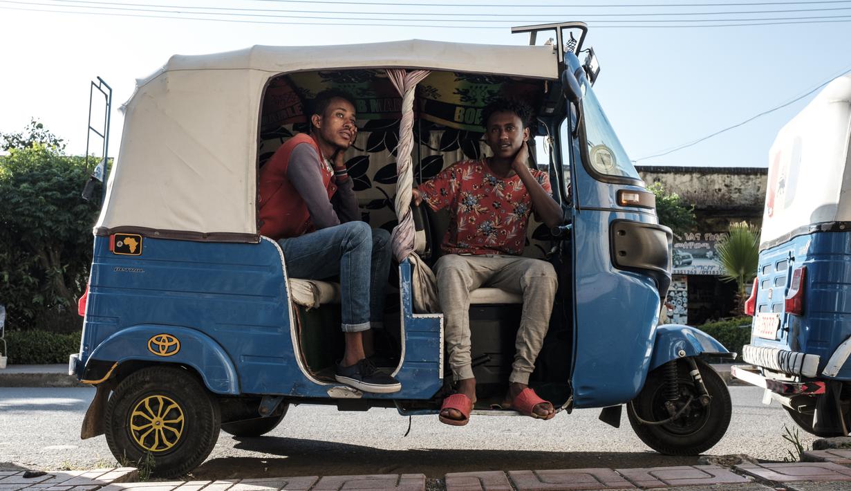 Dua anak muda duduk di sebuah Bajaj, di Kota Gondar, Ethiopia pada 09 November 2020. (Photo by EDUARDO SOTERAS / AFP)