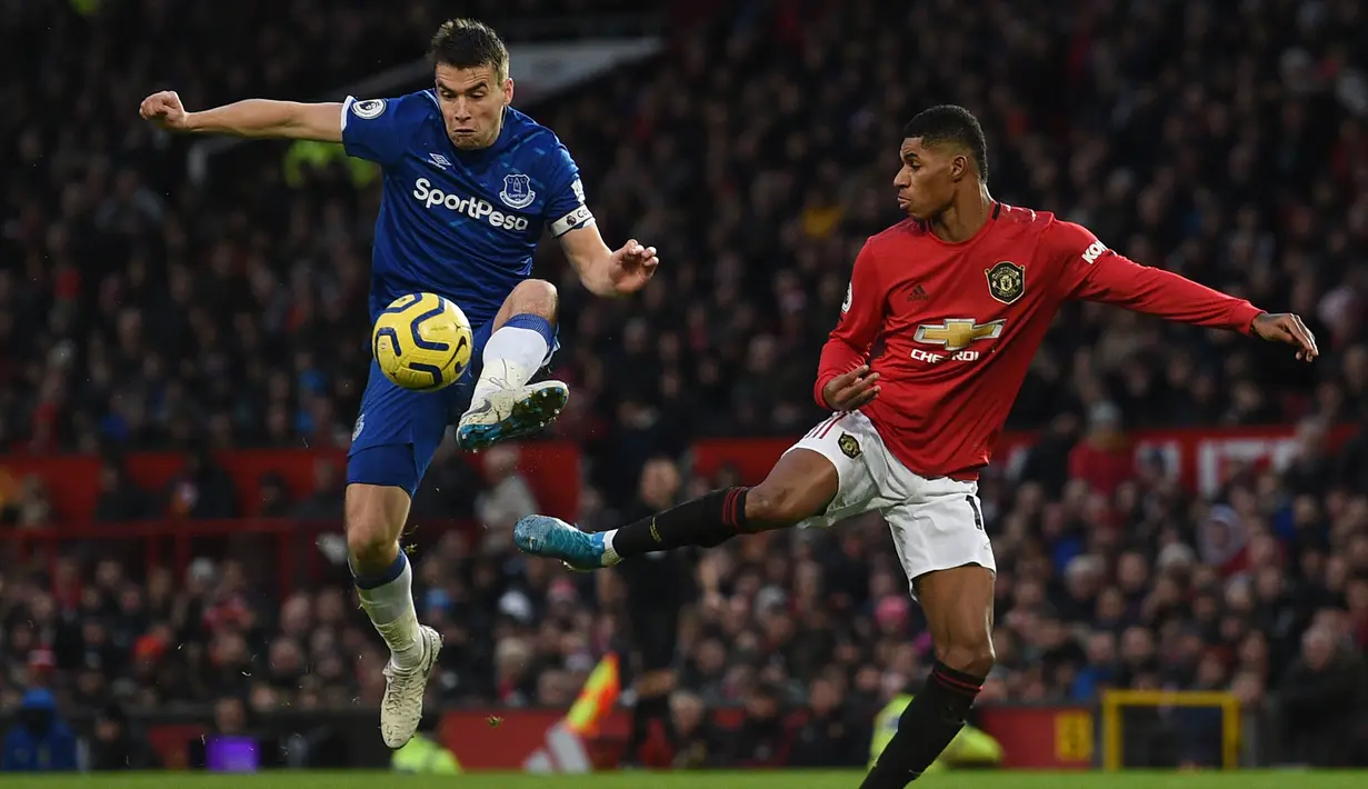 Bek Everton, Seamus Coleman, berebut bola dengan striker Manchester United, Marcus Rashford, pada laga Premier League di Stadion Old Trafford, Manchester, Minggu (15/12). Kedua klub bermain imbang 1-1. (AFP/Oli Scarff)