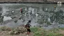 Petugas UPK Badan Air Dinas Lingkungan Hidup Provinsi DKI Jakarta membersihkan rerumputan dan sampah di dasar aliran Kanal Banjir Timur, Jakarta, Rabu (7/8/2019). Kemarau berkepanjangan mengakibatkan debit air Kanal Banjir Timur menyusut hingga dasar aliran terlihat. (merdeka.com/Iqbal Nugroho)