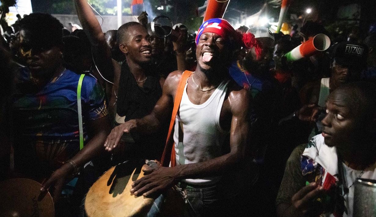 Warga Haiti turun ke jalan-jalan di Port-au-Prince saat merayakan lolosnya tim nasional mereka di putaran final Piala Dunia 2026, pada Selasa 18 November 2025 waktu setempat. Timnas Haiti memastikan lolos ke Piala Dunia 2026 usai mengalahkan Nikaragua dengan skor 2-0. (Clarens SIFFROY/AFP)