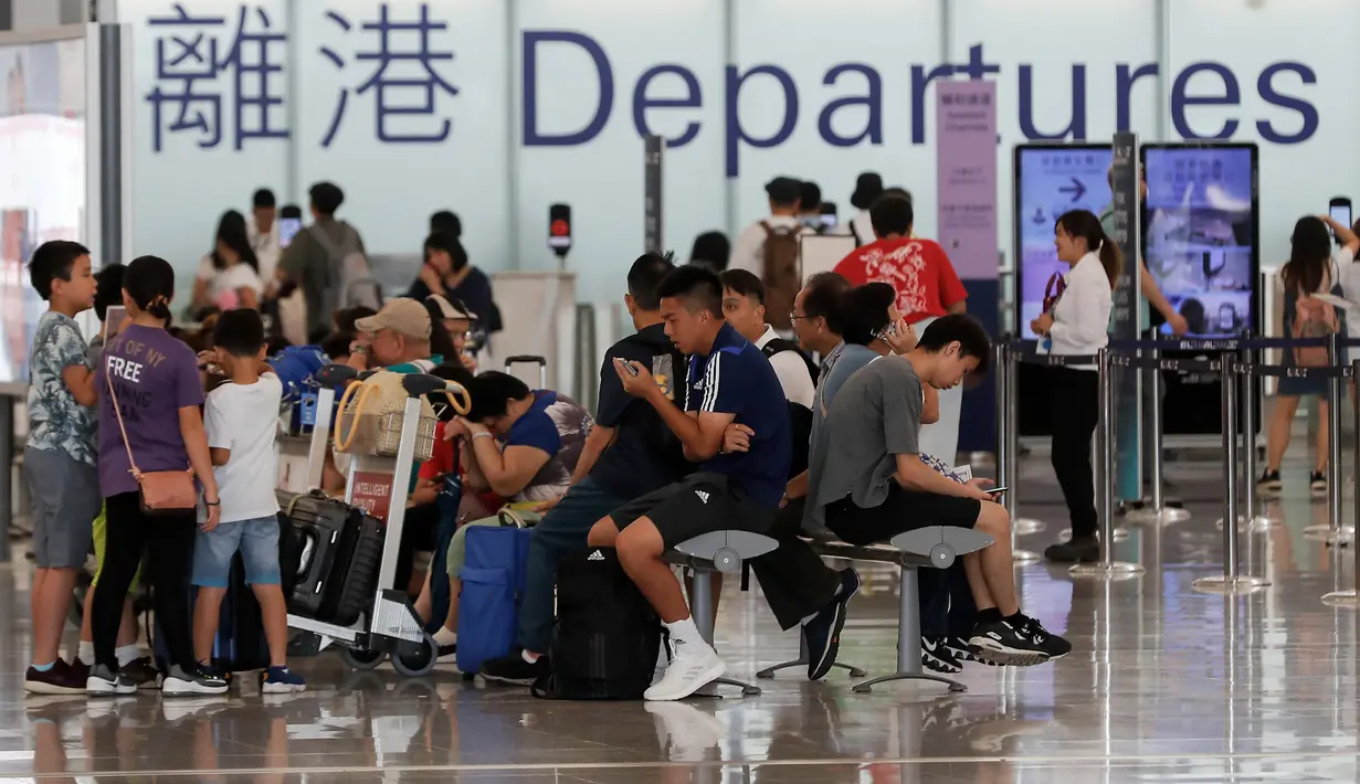Calon penumpang menunggu jadwal penerbangan di aula keberangkatan bandara di Hong Kong, Rabu (14/8/2019). Bandara Hong Kong kembali membuka penerbangan keberangkatan pada Rabu pagi setelah sempat lumpuh selama dua hari terakhir akibat demonstrasi. (AP/Vincent Thian)
