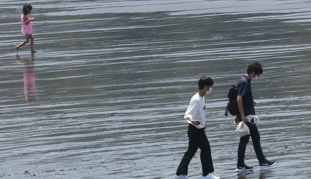 Orang-orang berjalan di pantai Katase-kaigan di Fujisawa, prefektur Kanagawa, dekat Tokyo, Senin (8/6/2020). Jepang mengangkat keadaan darurat coronavirus-nya, mengakhiri pembatasan secara nasional ketika bisnis mulai dibuka kembali. (AP Photo/Koji Sasahara)