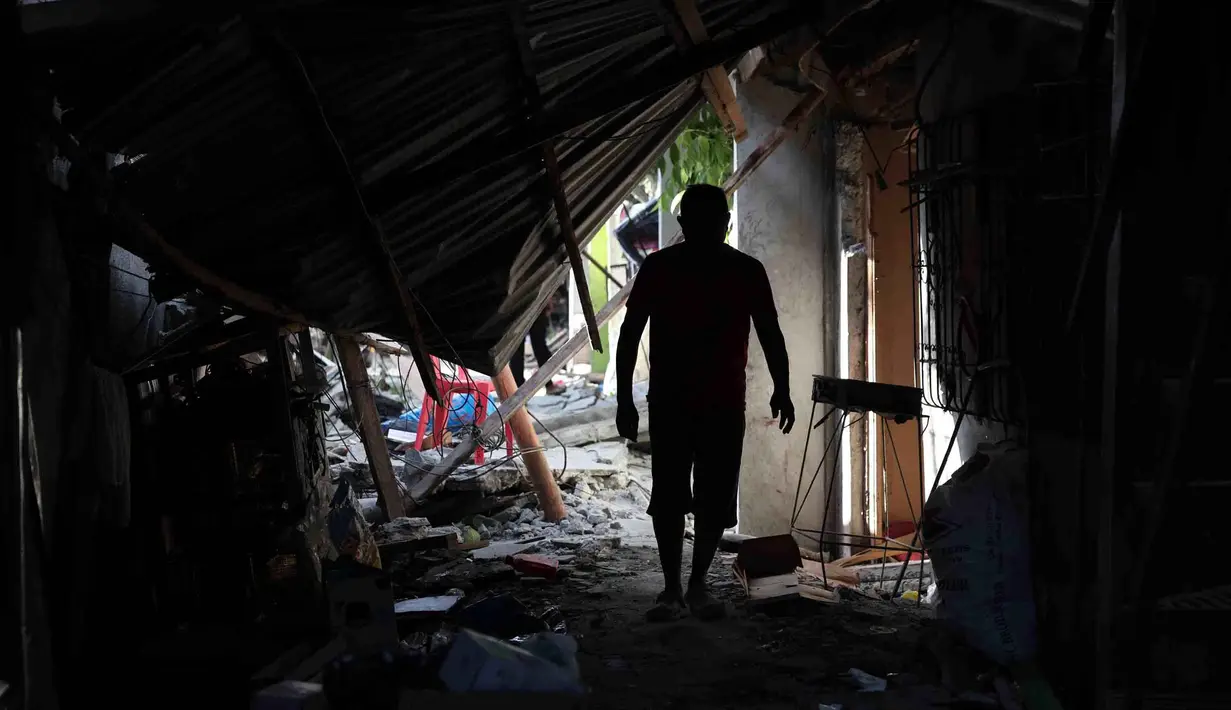Warga berjalan melewati puing-puing rumah yang rusak akibat gempa di General Santos, Filipina, Selasa 9 Juni 2026. (AP Photo/Basilio Sepe)