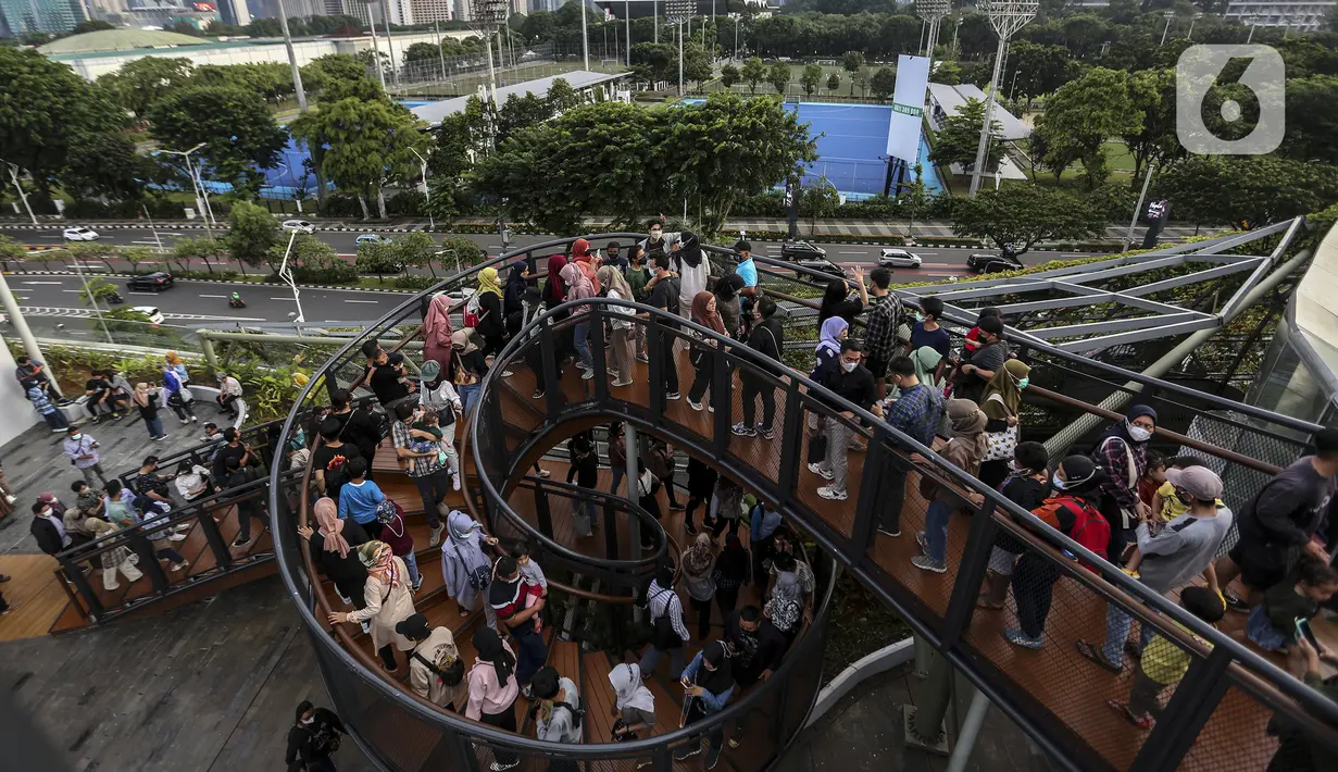 Warga memenuhi Skywalk Senayan Park saat mengisi libur Tahun Baru dengan menikmati pemandangan Kota Jakarta, Sabtu (1/1/2022). Warga ramai-ramai datang untuk berburu foto pada spot-spot yang instagramable di Skywalk Senayan Park. (Liputan6.com/Johan Tallo)