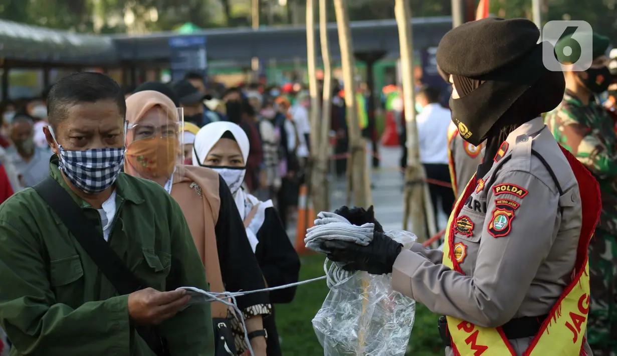 Personel polisi membagikan masker kepada calon penumpang kereta di area pedestrian Stasiun Terpadu Tanah Abang, Jakarta, Kamis (27/8/2020). Guna menekan penyebaran Covid-19, Polda Metro Jaya dan Kodam Jaya terus mengampanyekan pentingnya menaati protokol kesehatan. (Liputan6.com/Helmi Fithriansyah)