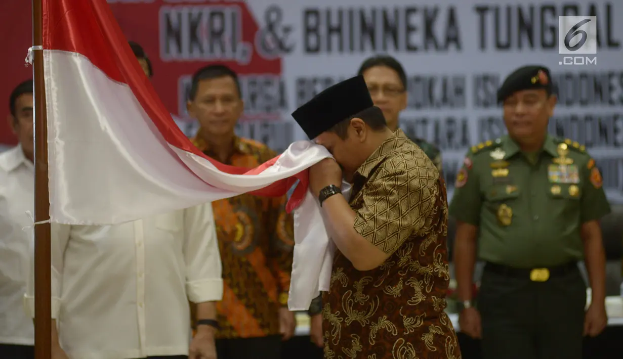 Anak pemimpin Darul Islam/Tentara Islam Indonesia (DI/TII) Sekarmaji Marijan Kartosuwiryo, Sarjono Kartosuwiryo mencium bendera Merah Putih saat pembacaan ikrar setia kepada Pancasila, UUD 45, NKRI dan Bhineka Tunggal Ika di Kemenko Polhukam, Jakarta, Selasa (13/8/2019). (merdeka.com/Imam Buhori)
