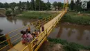 Sejumlah anak berpose saat difoto di jembatan gantung di kawasan Tanjung Barat, Jakarta Selatan, Senin (22/5). Sejumlah warga mengeluhkan desain konstruksi jembatan yang kerap menjadi tempat bermain anak. (Liputan6.com/Immanuel Antonius)