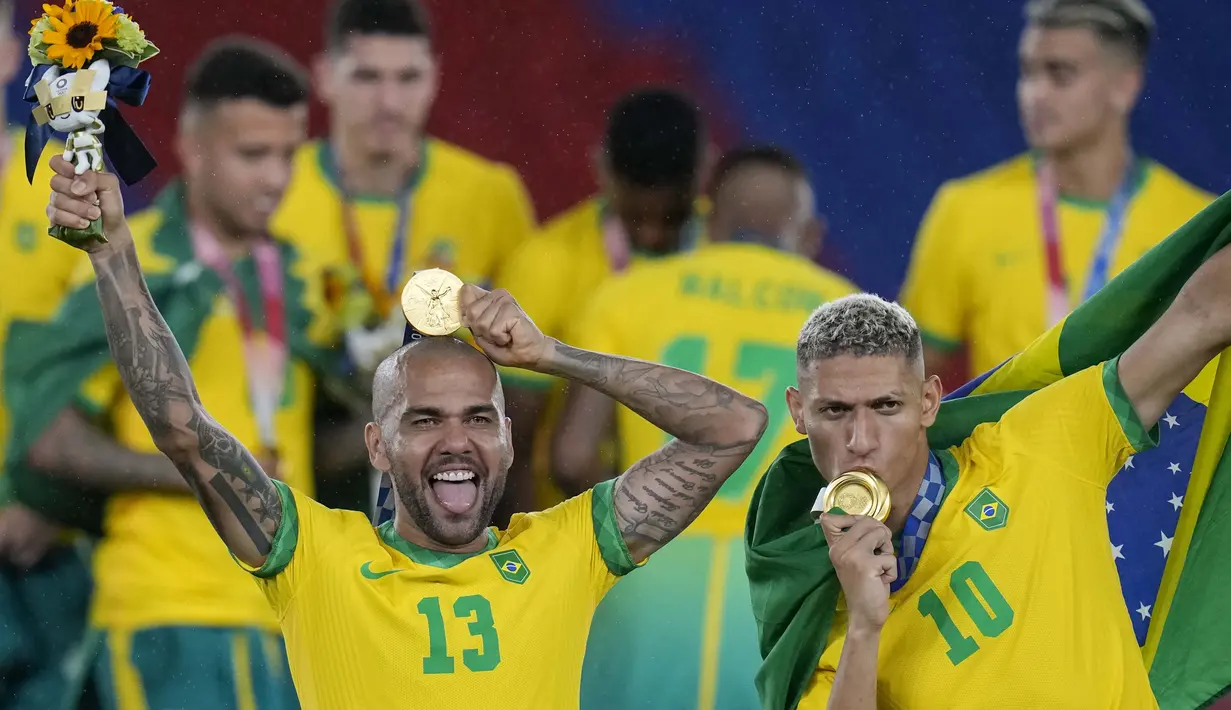 Dani Alves dan Richarlison berpose dengan medali emas Olimpiade Tokyo 2020. Bagi Brasil, ini adalah medali emas kedua di Olimpiade, setelah sebelumnya menjadi juara pada 2016 di Rio de Janeiro. (Foto: AP/Fernando Vergara)