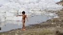 Seorang anak bermain di Sungai Yamuna yang tercemar di New Delhi, Sabtu (8/7). Akibat pertumbuhan populasi dan industrialisasi, Yamuna menjadi salah satu sungai paling tercemar di dunia. (DOMINIQUE FAGET / AFP)