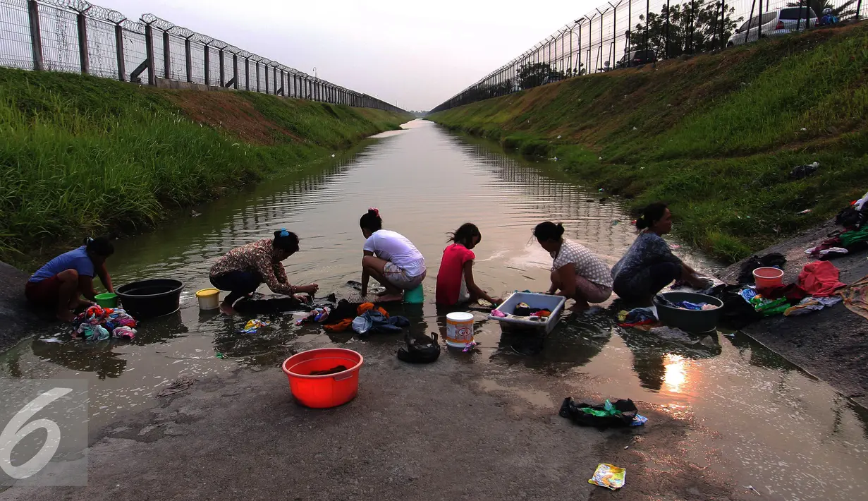 Warga mencuci pakaian di sungai yang menjadi pembatas di area Bandara Soetta, Tangerang (28/9/2015). Akibat kemarau panjang membuat pasokan air menjadi kering sehinga warga yang bermukim nekat menerobos pagar untuk mencuci. (Liputan6.com/Angga Yuniar)