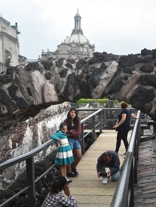 Pengunjung foto di Templo Mayor di kota Meksiko, (12/8). Situs arkeologi Templo Mayor saat ini terletak di sebelah timur laut Zocalo. (AFP Photo/Rodrigo Arangua)