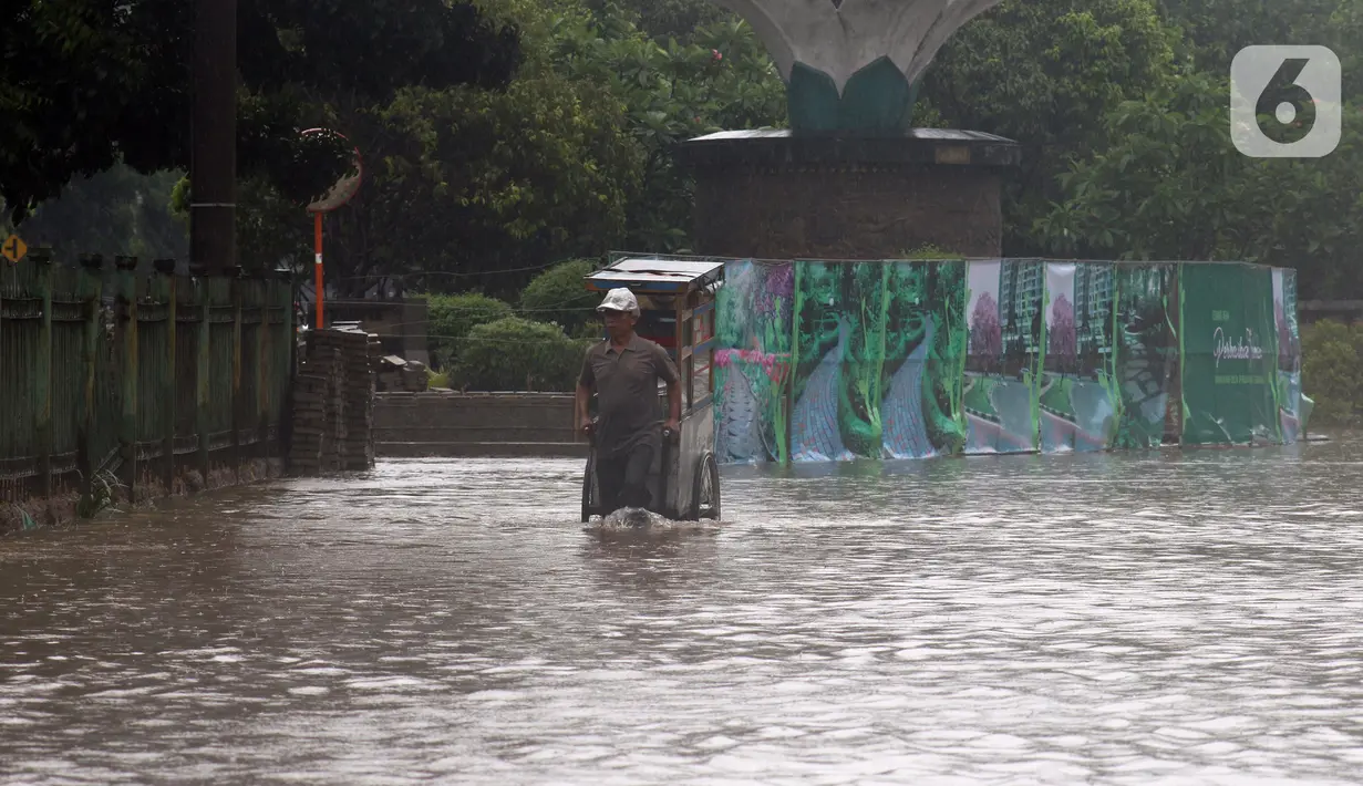 Pedagang melintasi Jalan Di Panjaitan dekat Halte Transjakarta Cawang Soetoyo yang banjir, Jakarta, Rabu (1/1/2020). Hujan yang mengguyur Jakarta sejak Selasa sore (31/12/2019) mengakibatkan banjir di sejumlah titik di Jakarta. (Liputan6.com/Helmi Fithriansyah)