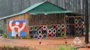 Siswa bermain di tengah hujan di luar Coconut School, Taman Nasional Kirirom Kamboja, 1 Oktober 2018. Hampir seluruh bangunannya menggunakan sampah dan limbah daur ulang yang dikumpulkan murid-muridnya. (TANG CHHIN Sothy/AFP)