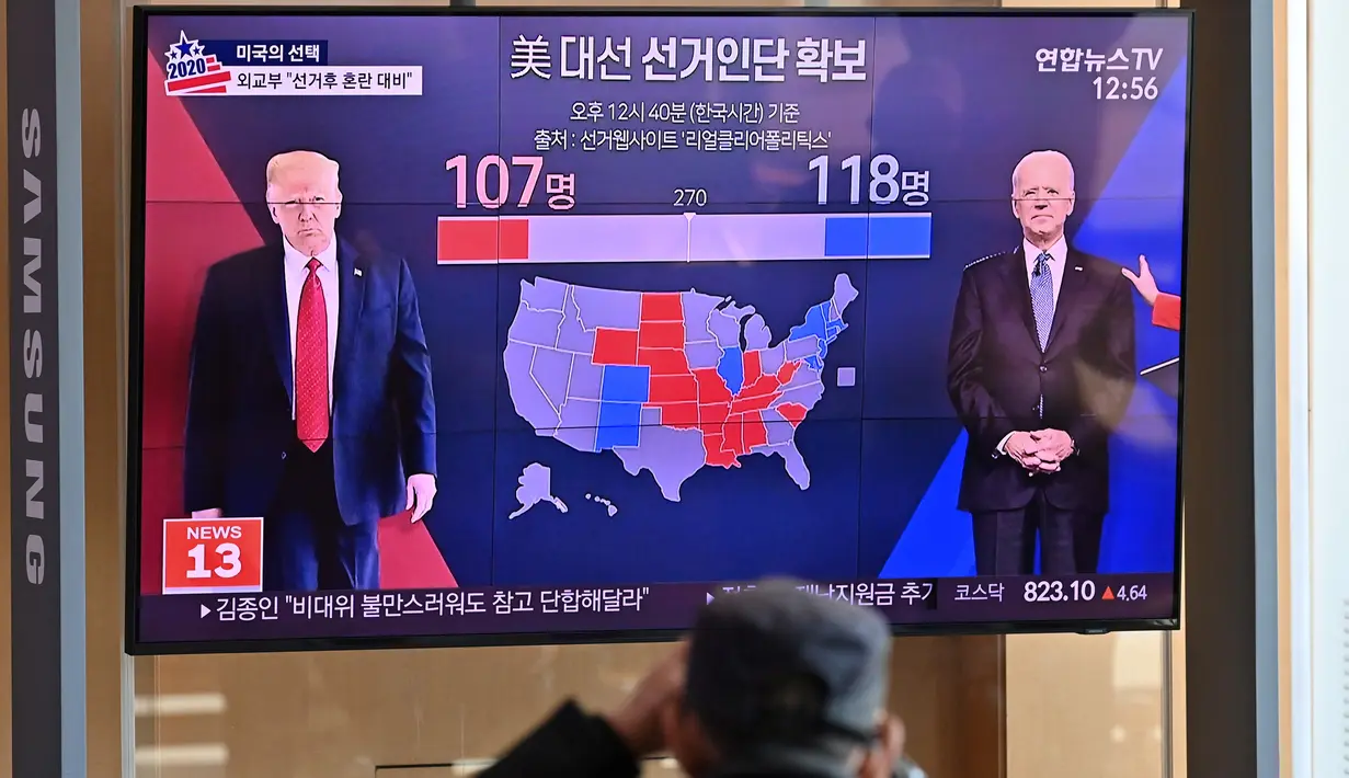 Orang-orang menonton program berita televisi tentang pemilihan presiden (pilpres) AS yang menampilkan gambar Presiden Donald Trump (kiri) dan calon presiden dari Partai Demokrat Joe Biden (kanan), di sebuah stasiun kereta api di Seoul, Korea Selatan pada Rabu (4/11/2020). (Photo by Jung Yeon-je/AFP)