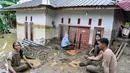 Air luapan sungai menerjang pemukiman warga dan memutus akses transportasi. Tampak dalam foto, warga membersihkan lumpur tebal dari pintu masuk rumah yang terendam banjir bandang di Meureudu, Kabupaten Pidie Jaya, Provinsi Aceh, Jumat 28 November 2025. (CHAIDEER MAHYUDDIN/AFP)