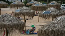 Panel surya terpasang pada sejumlah payung di pantai dekat Balai Kota Vari-Voula-Vouliagmeni, Yunani, Selasa (21/7/2020). Para pengunjung pantai dapat berkontribusi terhadap upaya penghematan energi menggunakan tenaga surya. (Xinhua/Lefteris Partsalis)