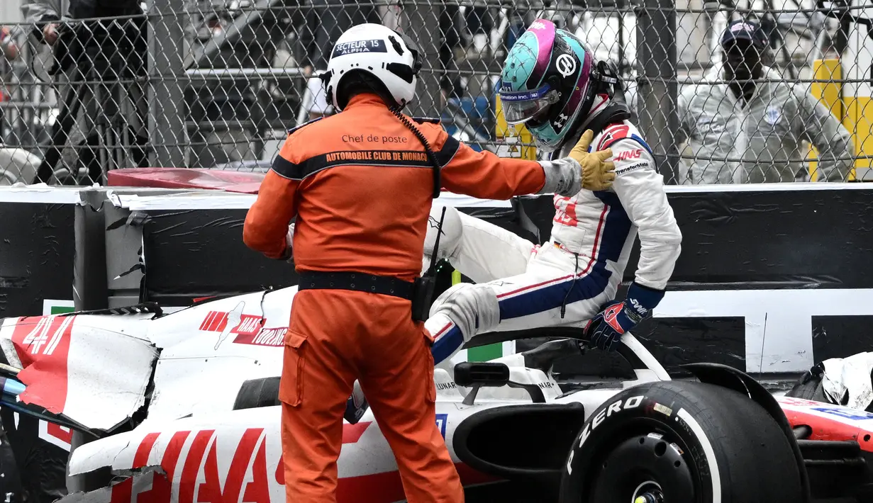 Pembalap Tim Haas, Mick Schumacher dibantu oleh marshall keluar dari mobilnya usai mengalami kecelakaan saat Formula 1 GP Monako yang berlangsung di Circuit de Monaco, Minggu, 29 Mei 2022. (AFP/Loic Venance)
