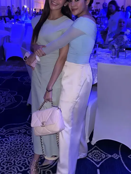 Ririn Dwi Ariyanti mengenakan long dress sleeveless baby blue dipadukan tas Chanel putih. Naysila Mirdad mengenakan atasan off shoulder lengan panjang dipadukan celana panjang putih satin. [@ririndwiariyanti]
