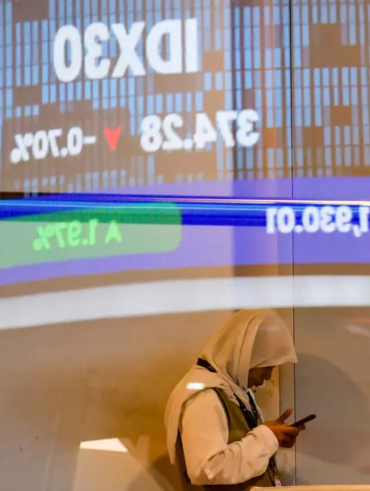 Seorang wanita terlihat di balik monitor kaca yang menampilkan Indeks Harga Saham Gabungan (IHSG), yang anjlok signifikan selama pembukaan pasar, di gedung Bursa Efek Indonesia di Jakarta pada Rabu 13 Mei 2026. (BAY ISMOYO/AFP)