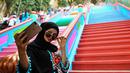Pengunjung berswafoto dengan latar belakang tangga 272 langkah yang baru dicat, jalan untuk menuju kuil Batu Caves di Kuala Lumpur, 30 Agustus 2018. Pro kontra dialami oleh objek wisata religi yang bersejarah di Malaysia tersebut. (AFP/Manan VATSYAYANA)