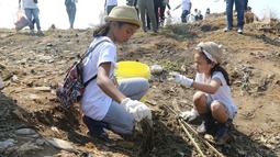 Dua anak membersihkan sampah di pantai timur ancol, Jakarta, Minggu (18/8/2019).  Gerakan Menghadap Laut 2.0 akan digelar serentak di lebih dari 100 titik lokasi di seluruh Indonesia. (Liputan6.com/Herman Zakharia)