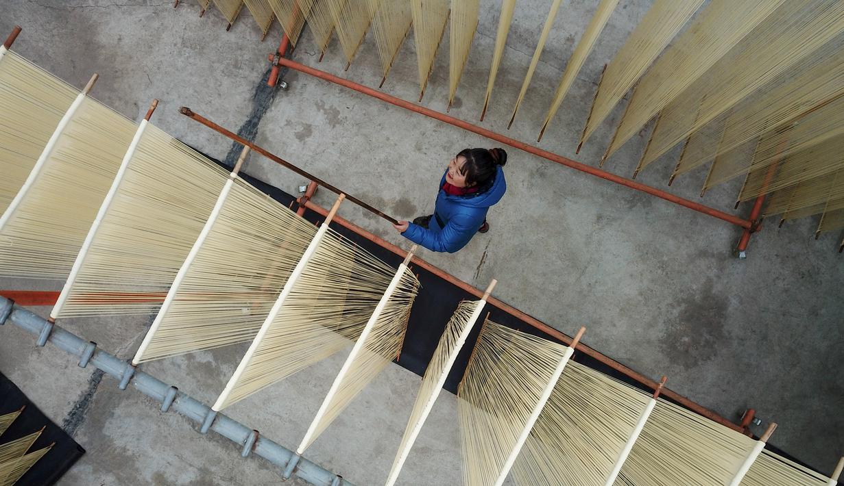 Foto dari udara pada 30 November 2020 menunjukkan seorang penduduk desa mengeringkan mi di Desa Huangjiazhuang di Distrik Maiji, Kota Tianshui, Provinsi Gansu, China barat laut. Proses pembuatan mi di desa tersebut memiliki sejarah lebih dari 200 tahun. (Xinhua/Ma Xiping)