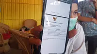 Pemilik Perusahaan Batik Tanah Liek Pusako Mande menunjukkan izin usaha pengadaan alat kesehatan. (Liputan6.com/ Novia Harlina)