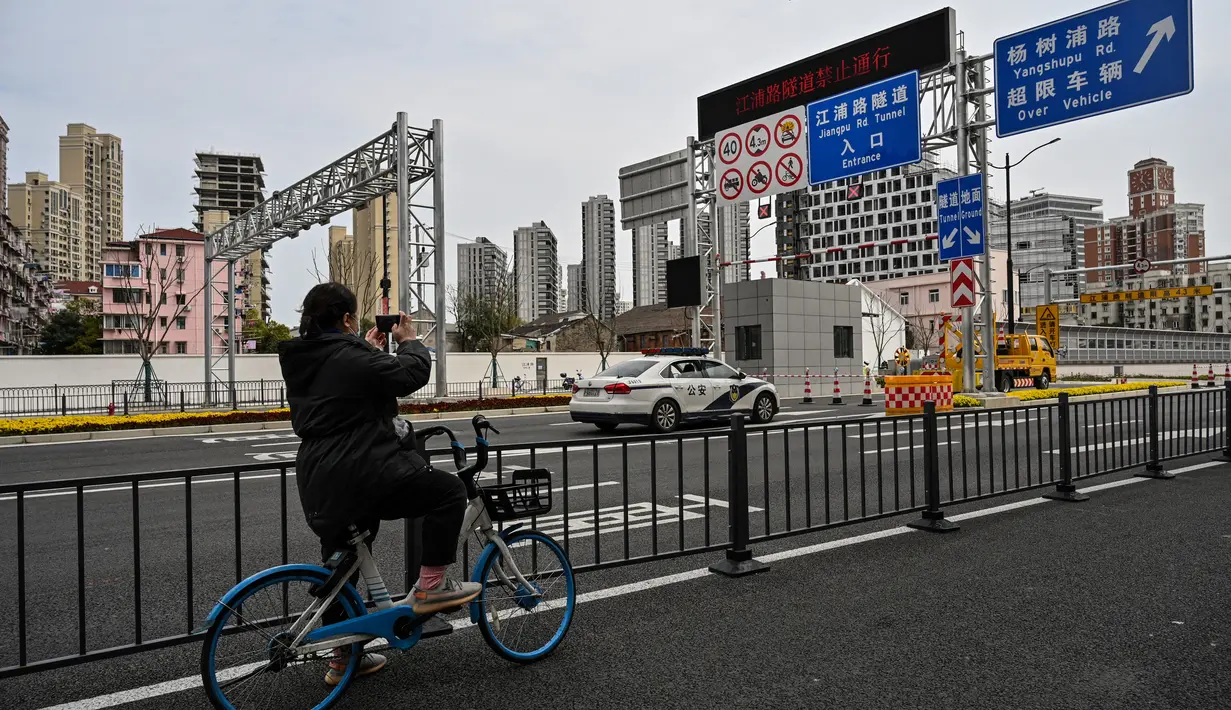 Seorang wanita mengambil gambar salah satu akses yang terkunci ke terowongan ke arah distrik Pudong yang dikunci sebagai tindakan melawan virus corona Covid-19, di Shanghai (28/3/2022). (AFP/Hector Retamal)
