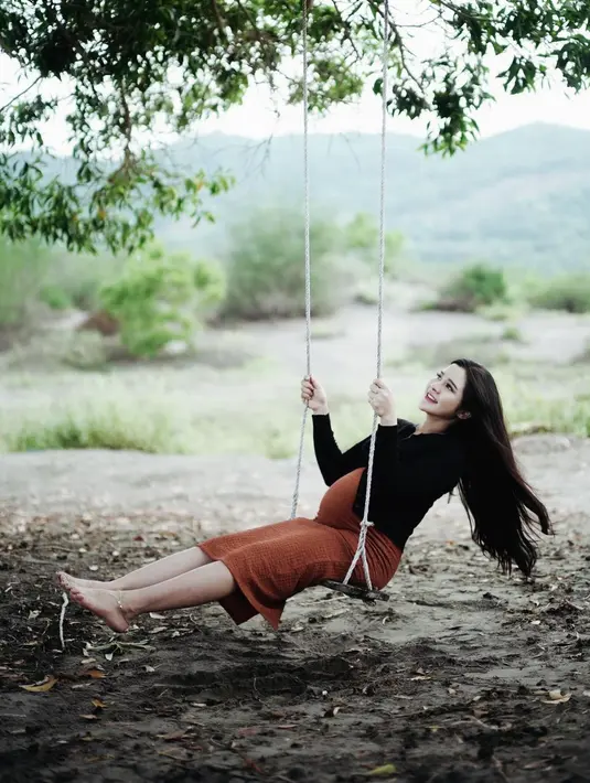 Sambil bermain ayunan, kali ini Bella tampil simple pakai dress cokelat dan cardigan hitam sambil bertelanjang kaki.